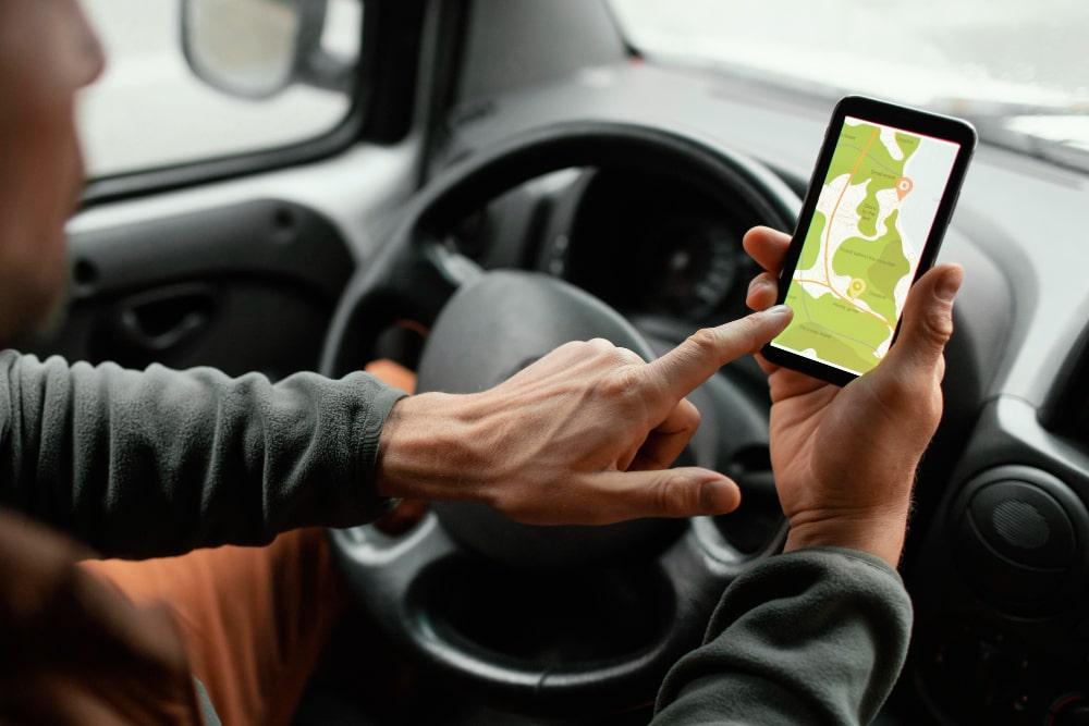 Une personne consultant une application de traceur GPS sur son smartphone pendant qu'elle conduit
