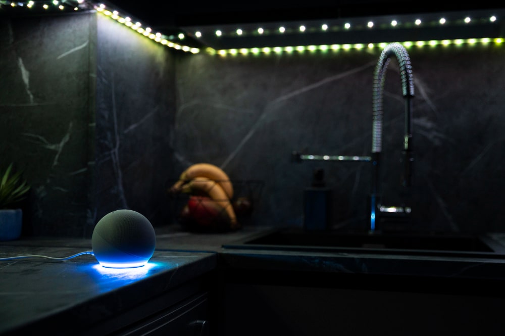 Un robinet d'évier moderne d'où coule de l'eau illuminée par des "gadgets LED" changeant de couleur, créant un effet visuel spectaculaire dans une salle de bain