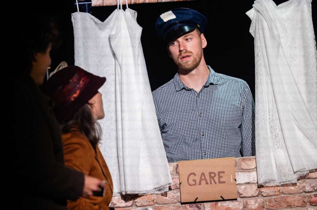 Scène de théâtre capturant un homme en uniforme et une femme regardant dans la même direction.