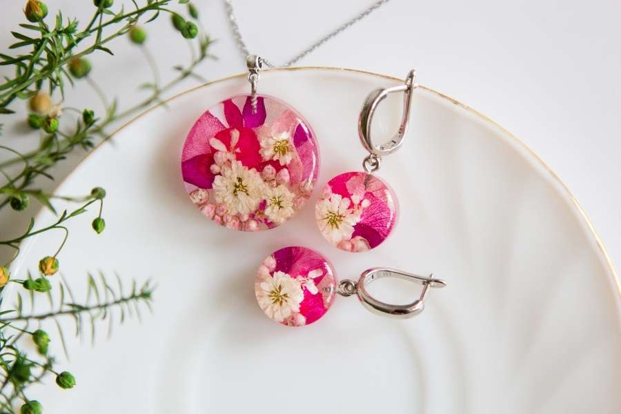 Bijoux floraux en résine époxy. Collier et boucles d’oreilles en résine époxy avec des fleurs séchées roses et blanches.
