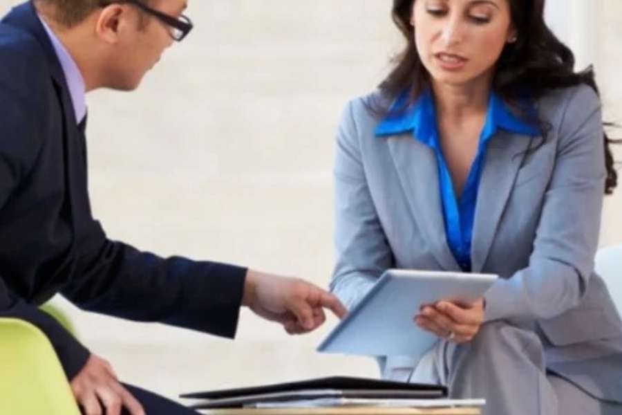 Deux professionnels discutent d’un programme de certifications en ligne reconnues sur une tablette.