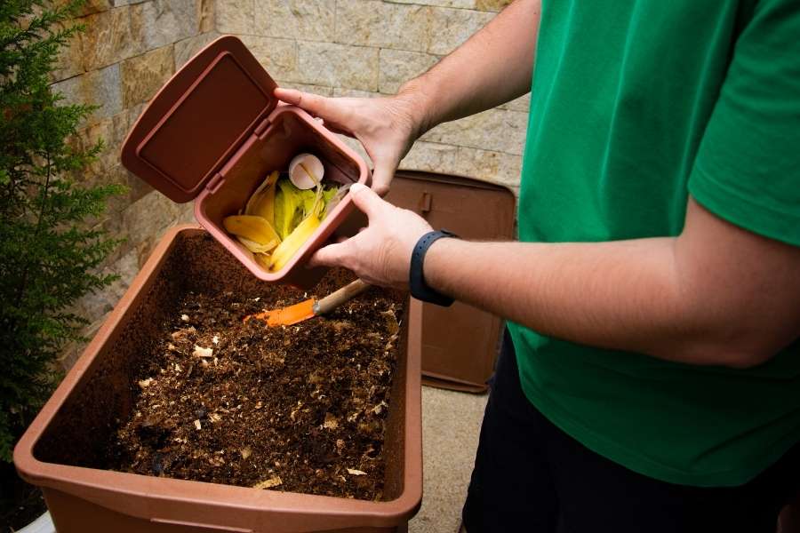 Un habitant ajoute des déchets organiques dans un bac à compost pour encourager le compostage en milieu urbain.