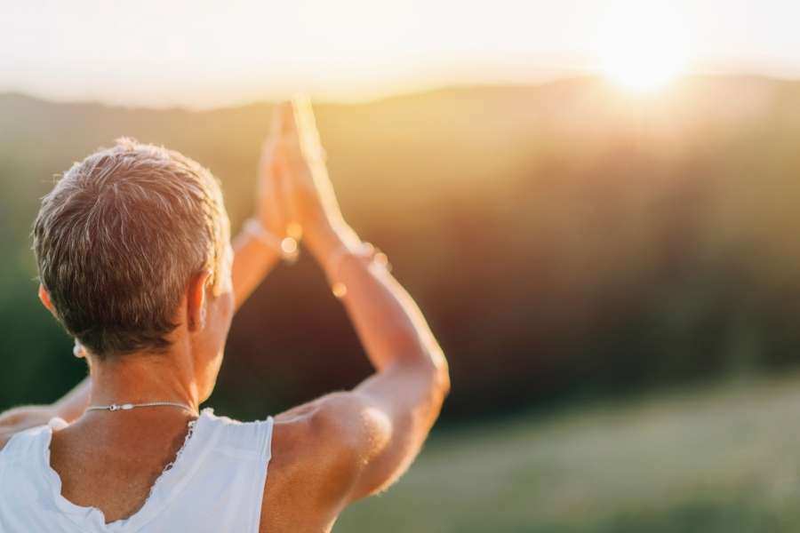Personne pratiquant la méditation au lever du soleil pour développer son intuition et la clarté intérieure.