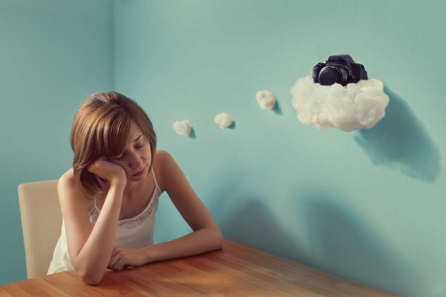 Jeune femme songeuse regardant un nuage en forme de pensée, représentant les rêves récurrents.