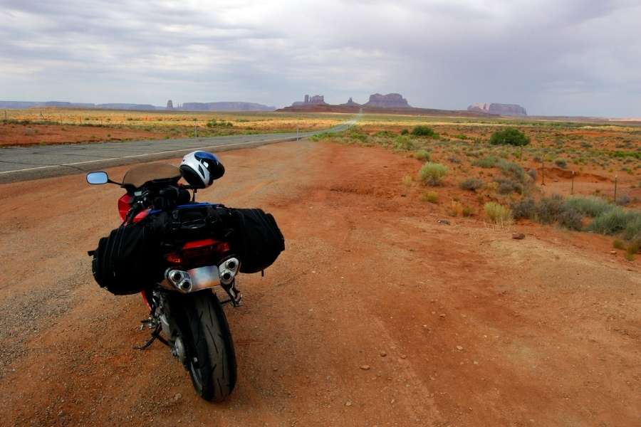 Moto équipée pour un road trip garée sur une route désertique.