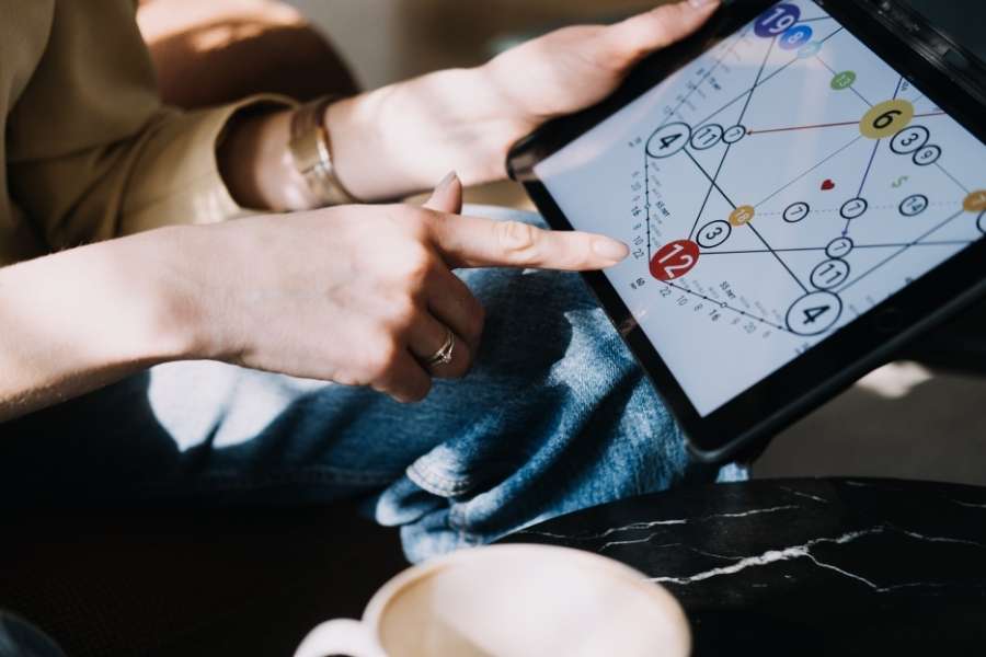 Thème personnel – Numérologie Personne analysant un thème personnel de numérologie sur une tablette numérique.