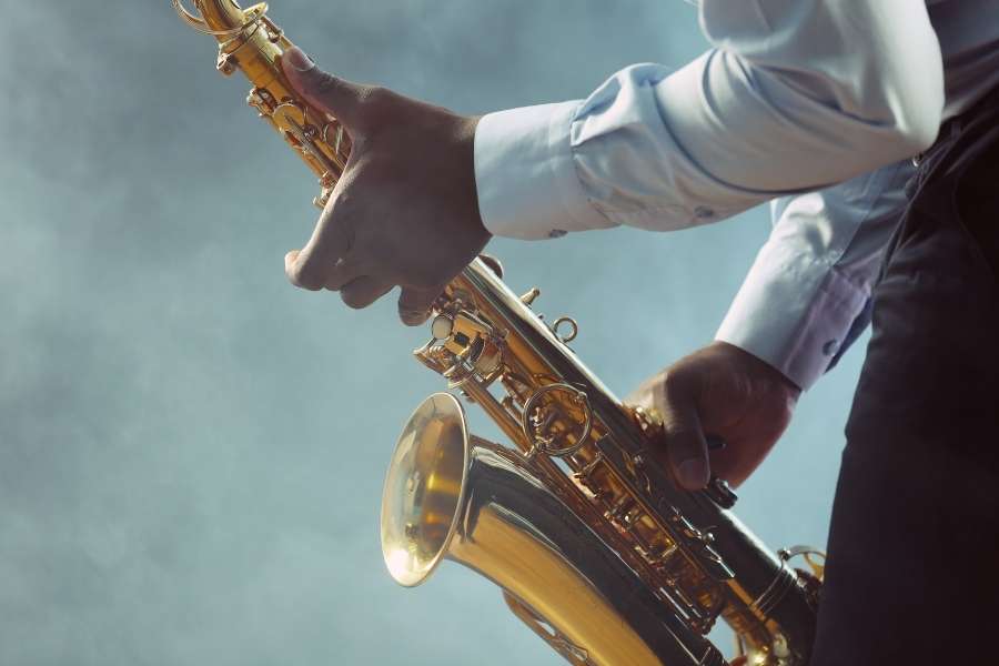 Performance inspirée des origines du jazz. Saxophoniste jouant sur scène dans une ambiance enfumée, symbole des origines du jazz.