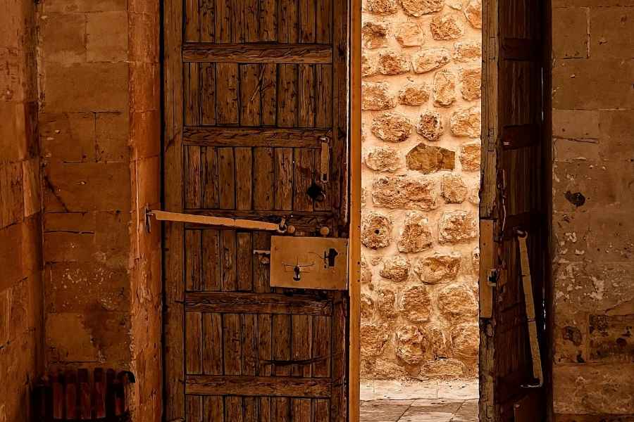Porte ancienne en bois massif dans une pièce rustique éclairée par la lumière du jour.