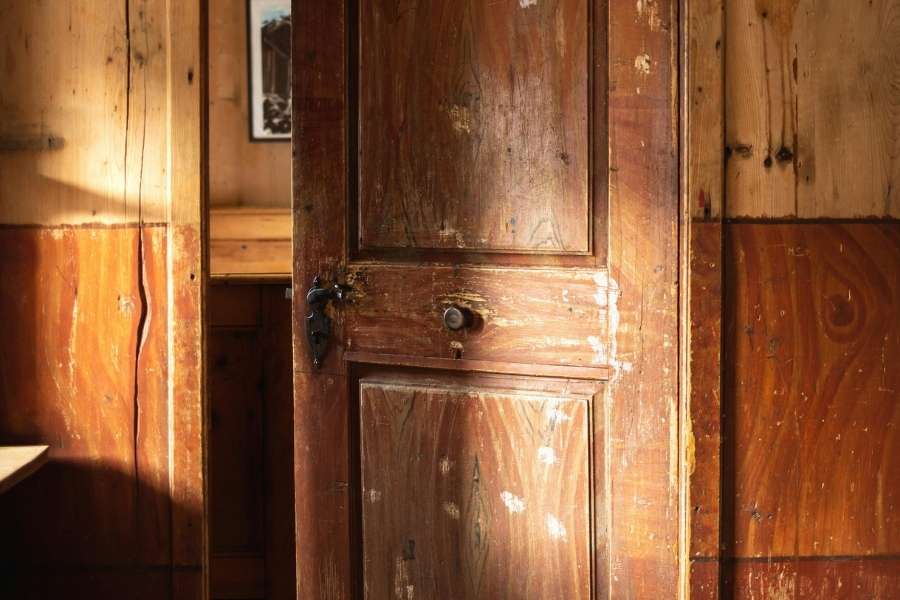 Porte ancienne en bois massif et mur de pierre. Porte ancienne en bois massif entrouverte laissant apparaître un mur en pierre.