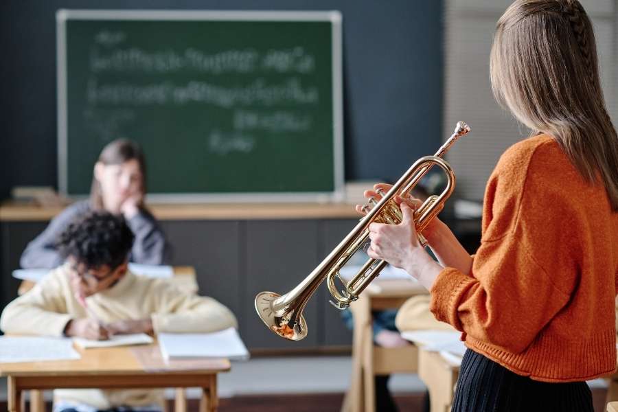 Cours de théorie musicale en classe Une professeure enseigne la théorie musicale avec une trompette dans une salle de classe.