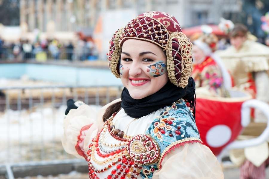 Costumes et traditions aux festivals littéraires. Femme souriante en costume folklorique participant à un événement culturel lié aux festivals littéraires.