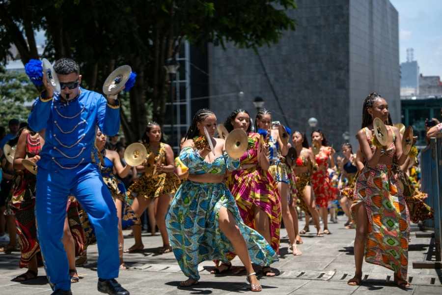 Groupe de danseurs en tenues colorées célébrant la culture et les festivals littéraires dans une rue animée.