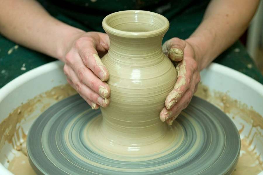 Artisan façonnant un vase en argile dans le cadre d’une poterie sans tour.