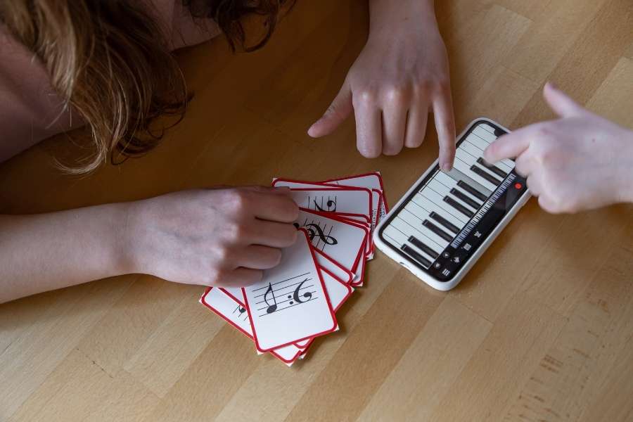 Des étudiants apprennent la théorie musicale avec des cartes de notes et un clavier virtuel sur smartphone.
