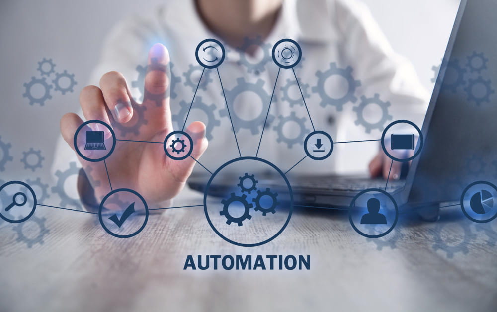 Photographie d'une personne interagissant avec une interface numérique holographique composée de rouages et d'icônes, montrant la collaboration et l’automatisation en action pour une gestion de flux de travail. Le mot 'AUTOMATION' est écrit en dessous.