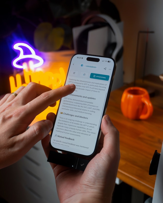 Mains tenant un smartphone affichant un résumé généré par IA sur les avancées de GPT-4, illustrant concrètement les applications intelligence artificielle au quotidien.